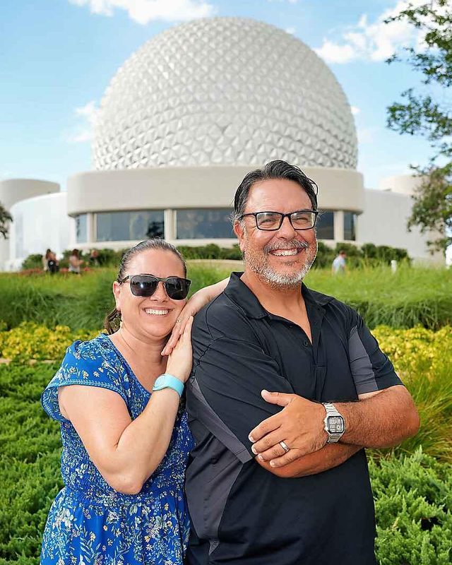 Heather and Matthew smiling in front of Spaceship Earth at EPCOT